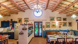A spacious kitchen with wooden beams, a dining area with a table set for four, and a cozy seating area with a sofa and chairs. - Belvilla by OYO Villa Dipinti (Serra San Quirico)