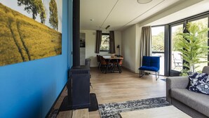 Un salon moderne doté d’une cheminée, d’un coin repas et de grandes fenêtres.
