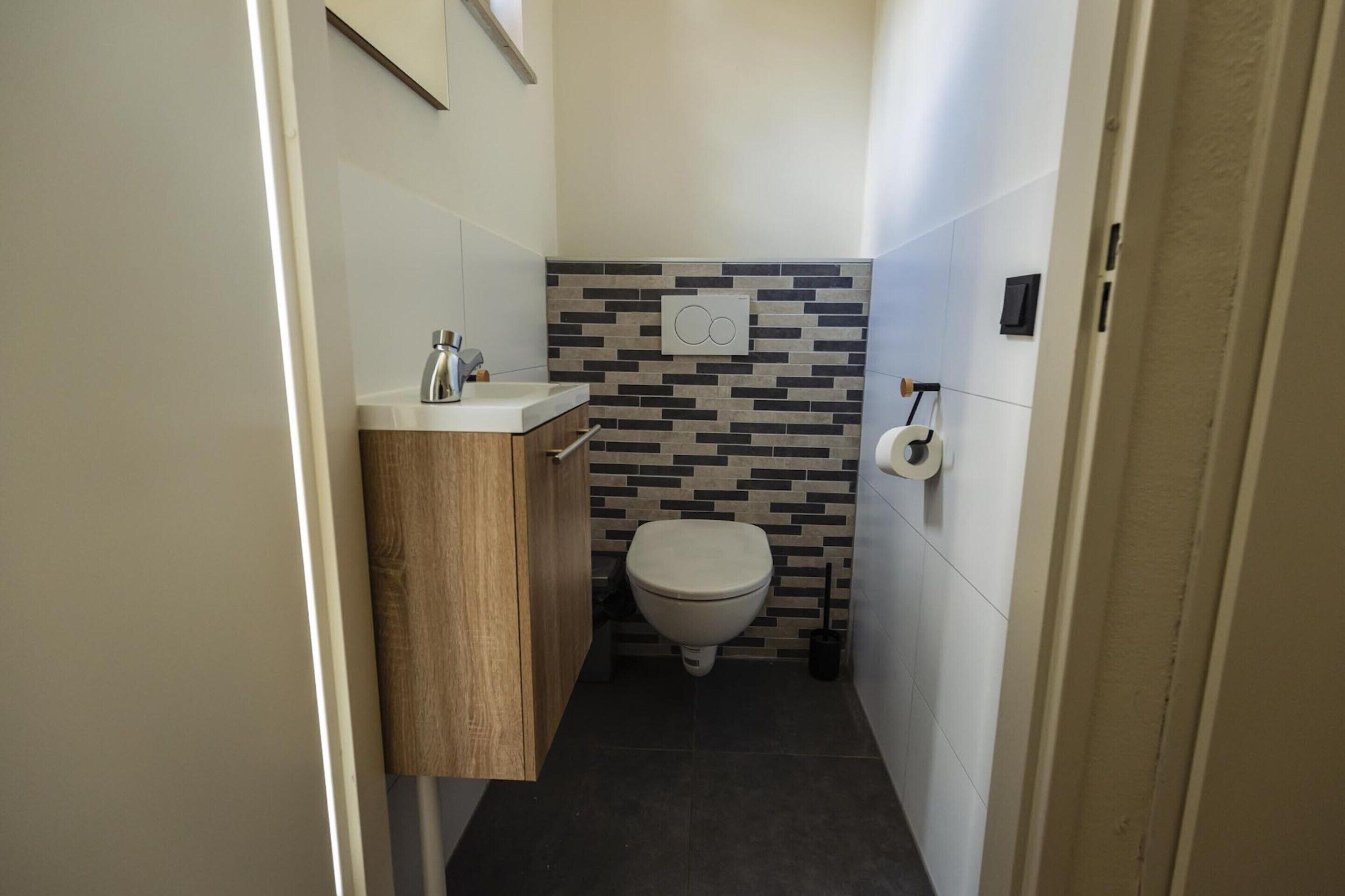 A compact bathroom with a toilet, a sink, and a wall-mounted towel rack.