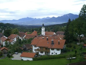 A village with traditional houses, a church with a bell tower, and mountains in the background. - House Marina Modern Retreat (Bad Kohlgrub)