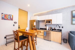A modern kitchen with white cabinets, a stainless steel refrigerator, a microwave, and a sink.