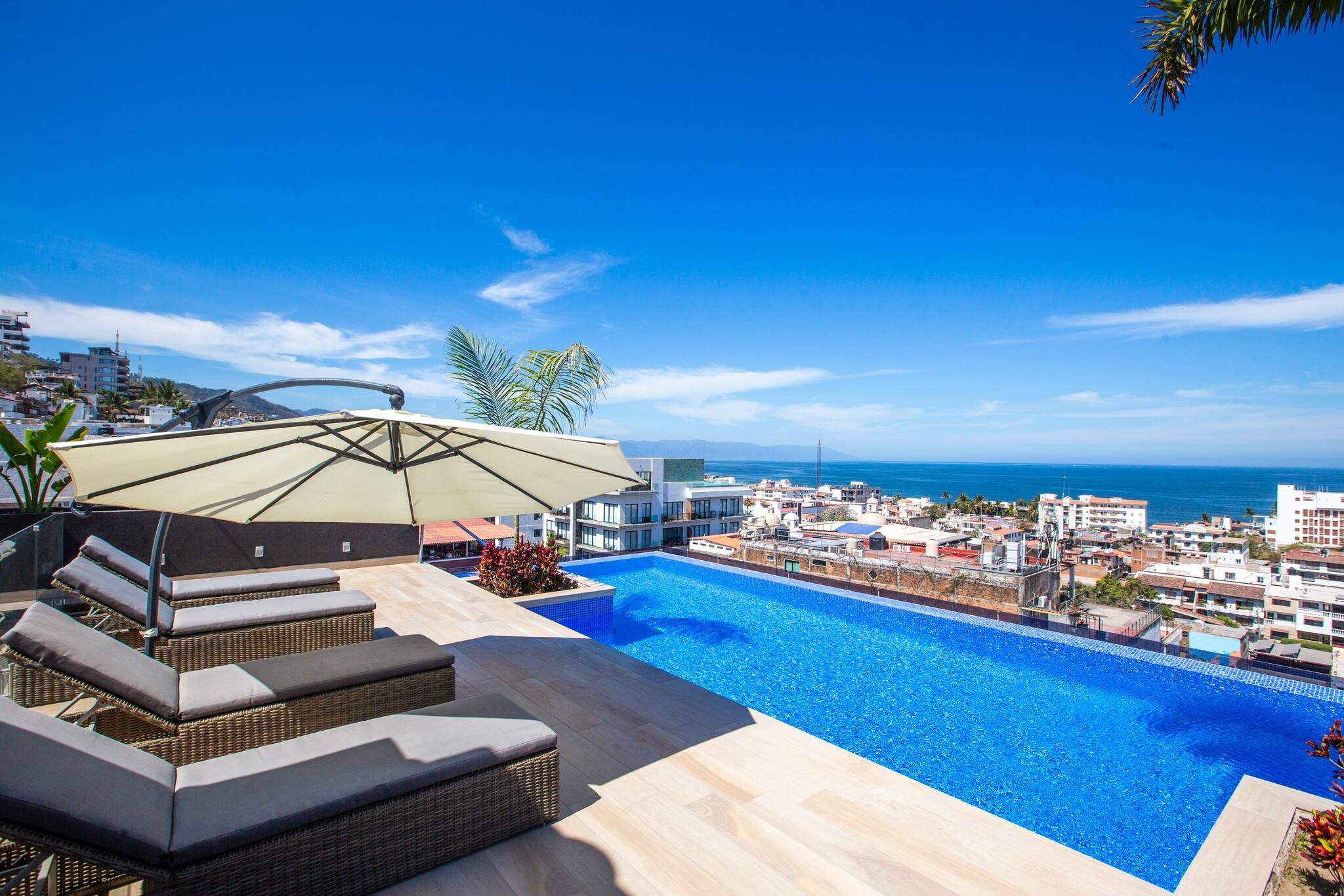 A rooftop pool with a view of the ocean and cityscape.