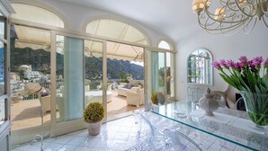Ein geräumiger Balkon mit freiem Blick auf die Berge und ein helles Interieur mit einem Glastisch und Stühlen.