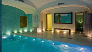 Ein Innenpool mit einer gefliesten Wand, einer Sitzbank und einer Sitzbank mit Handtuch.