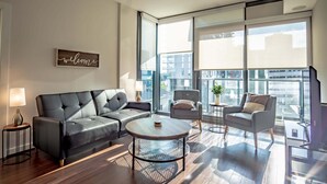 A modern living room with a sofa, armchairs, a coffee table, and a 'welcome' sign.
