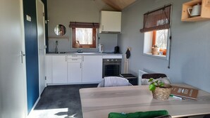 A compact kitchen with white cabinets, a built-in oven, and a window with blinds.