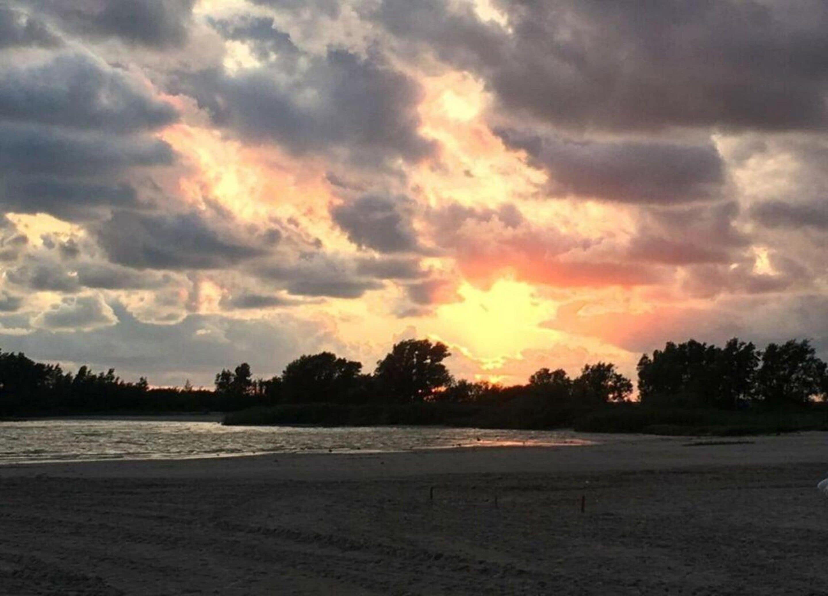 A beach with a sunset and clouds.