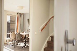 A staircase with a wooden handrail and a door leading to a dining area with a table and chairs. - Beautiful Holiday Home by the Water (Makkum)