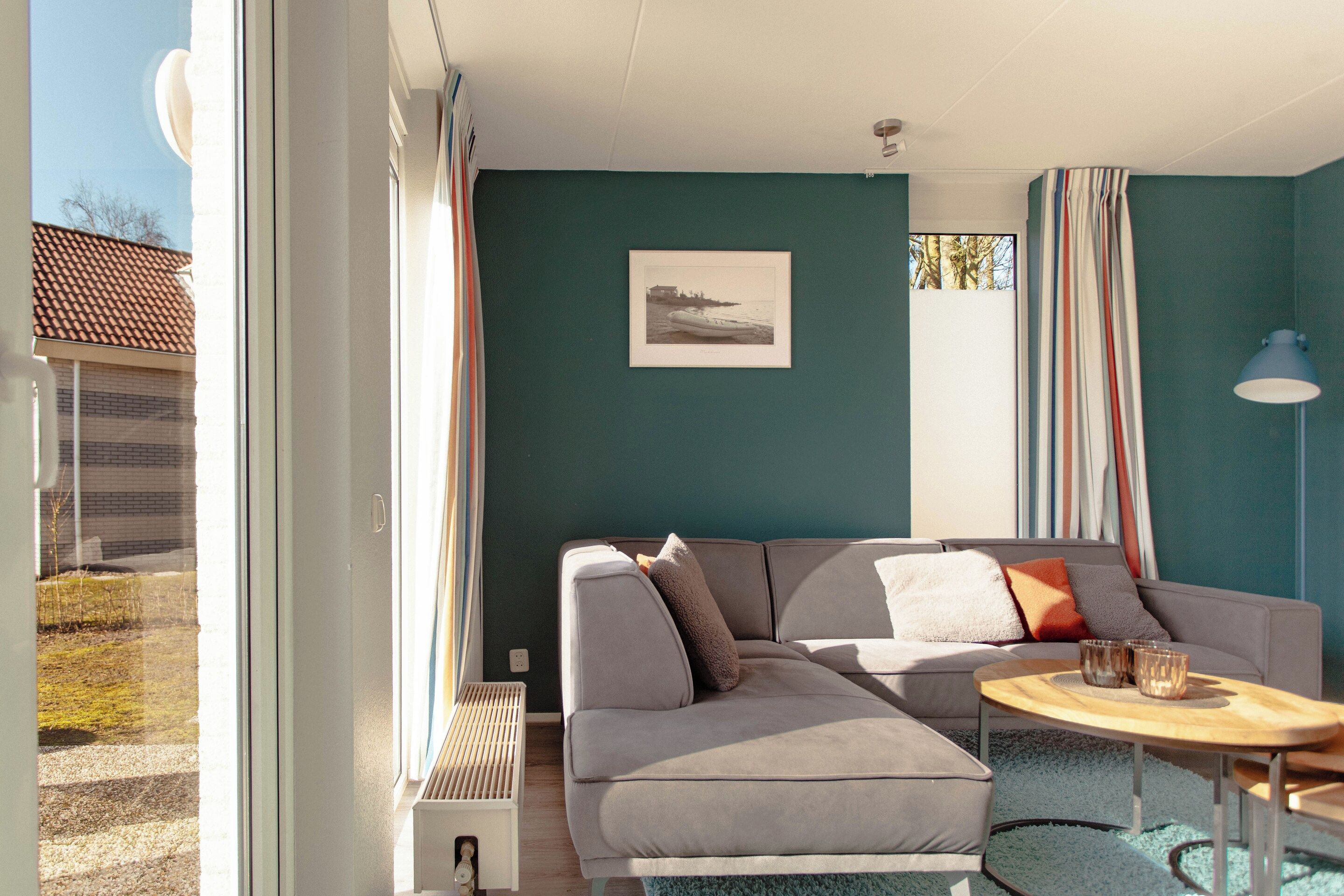 A modern living room with a grey sofa, a small round table, and a framed picture on the wall.