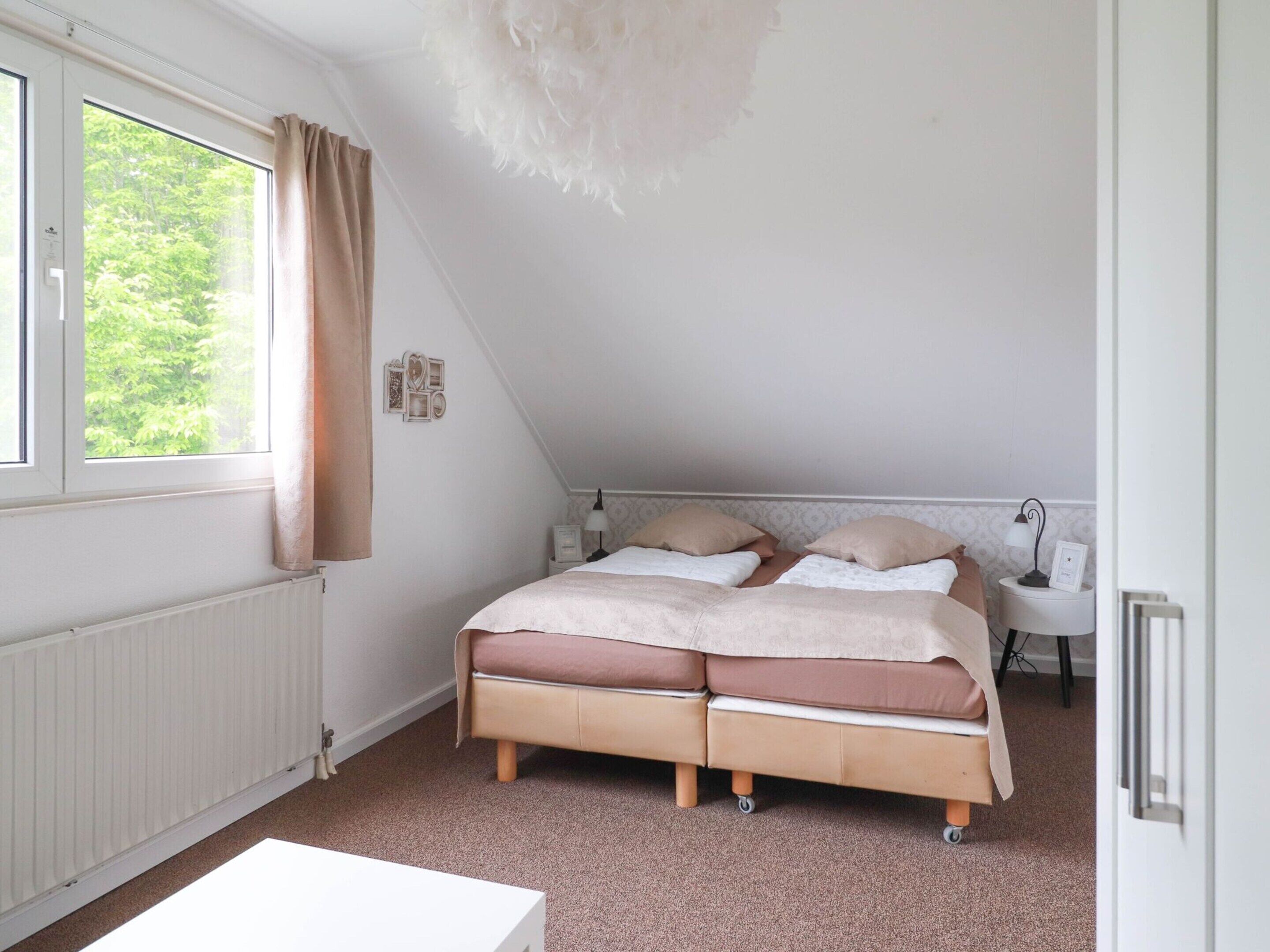 A bedroom with a bed, a desk, a chair, and a window with curtains.