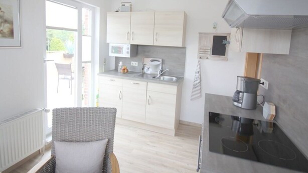 A modern kitchen with light wood cabinets, a built-in microwave, and a coffee machine. - Gerda in the Michaela House (Borkum)