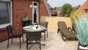 A patio with a round table and chairs, a grill, and a potted plant. - Gerda in the Michaela House (Borkum)