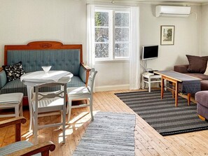 A cozy living room with a blue upholstered sofa, a white table, and a grey armchair. - 5 Person Holiday Home in Gamleby (Gamleby)