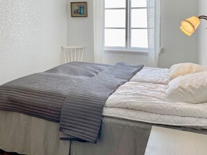 A bedroom with a bed, a window, a chair, and a wall-mounted lamp. - 5 Person Holiday Home in Gamleby (Gamleby)