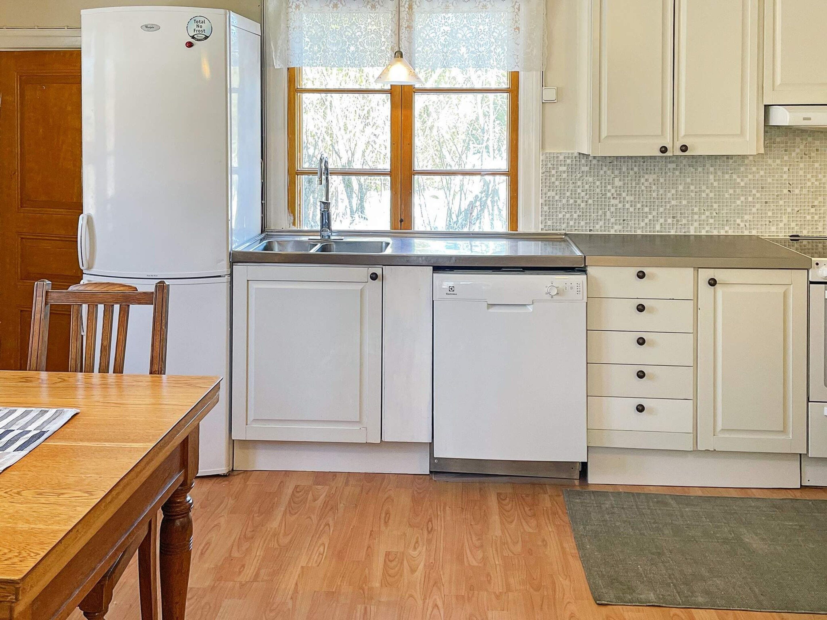A kitchen with a refrigerator, dishwasher, sink, and wooden cabinets.