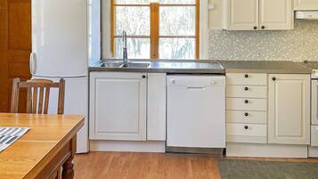 A kitchen with a refrigerator, dishwasher, sink, and wooden cabinets.