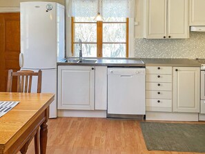 A kitchen with a refrigerator, dishwasher, sink, and wooden cabinets. - 5 Person Holiday Home in Gamleby (Gamleby)