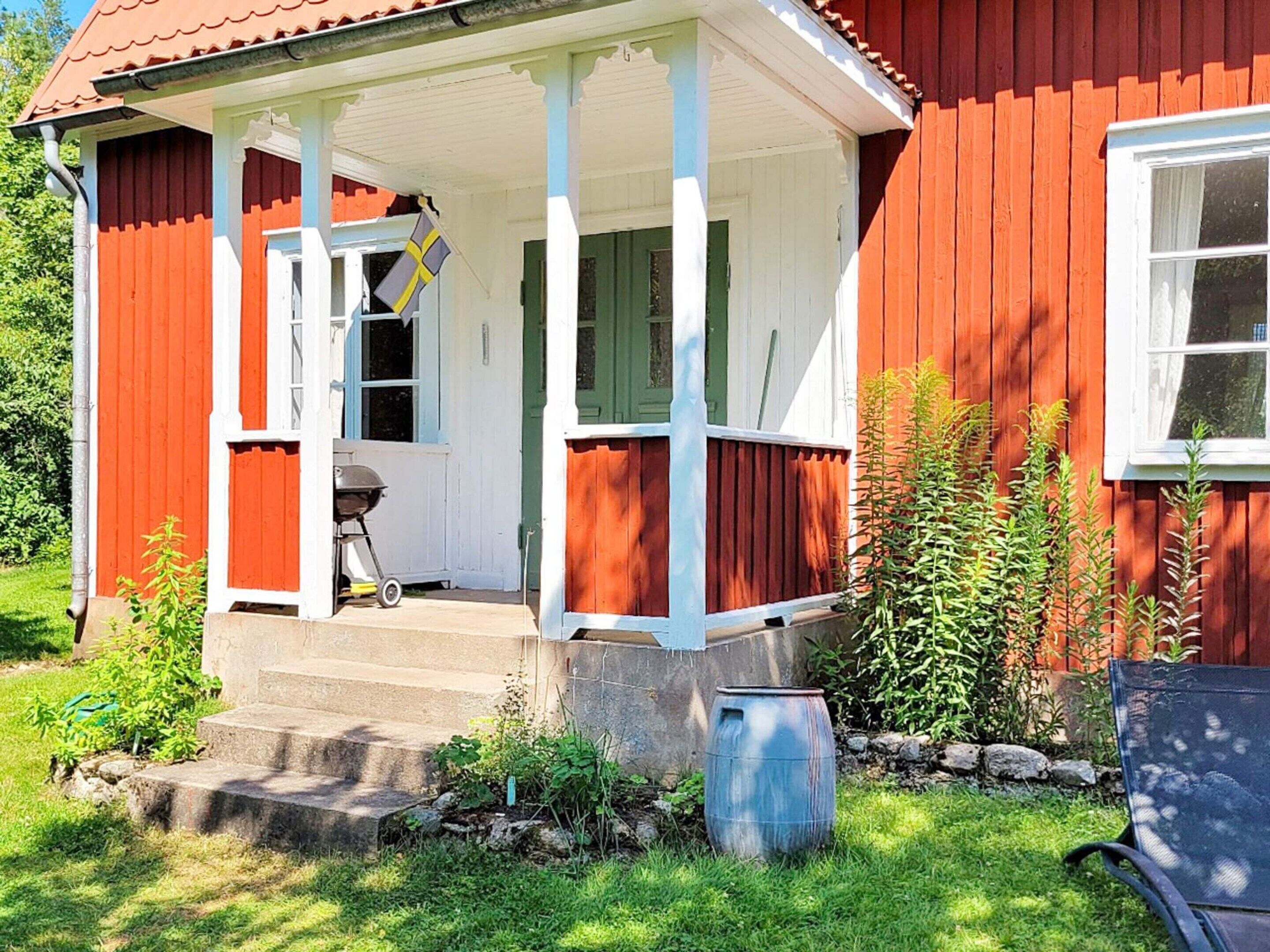 A red house with a porch, a grill, and a flag.