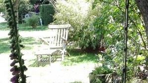 A garden with a bench, various plants, and a tree. - Long Comfortable Holiday Residence (Süderlügum)