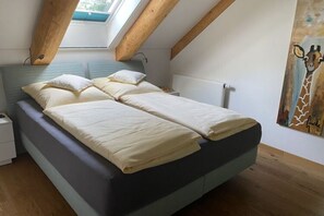 A bedroom with a bed, a nightstand, a painting, and a skylight.