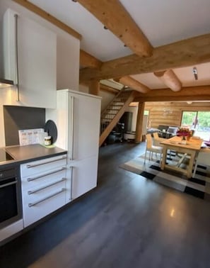 A modern kitchen with white cabinetry, a black countertop, and a staircase leading to a dining area.
