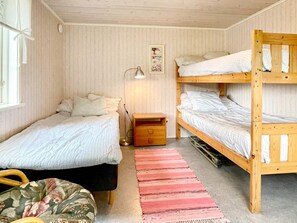 A room with two single beds, a bunk bed, a bedside table with a lamp, and a red striped rug. - 4 Person Holiday Home in Kopingsvik (Kopingsvik)