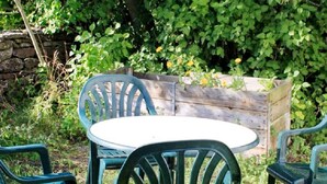A round table with four chairs, surrounded by greenery and a wooden structure. - 4 Person Holiday Home in Kopingsvik (Kopingsvik)
