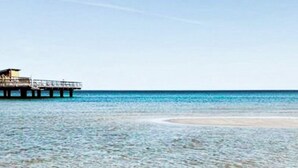 A pier extending into a clear blue sea with a small building at the end. - 4 Person Holiday Home in Kopingsvik (Kopingsvik)