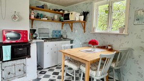 A kitchen with a microwave, sink, and wooden table with chairs. - 4 Person Holiday Home in Kopingsvik (Kopingsvik)