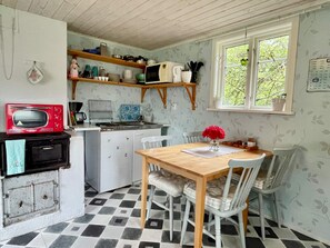 A kitchen with a microwave, sink, and wooden table with chairs. - 4 Person Holiday Home in Kopingsvik (Kopingsvik)
