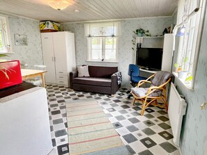 A compact living space with a sofa, a dining table, a television, and a window with a view. - 4 Person Holiday Home in Kopingsvik (Kopingsvik)
