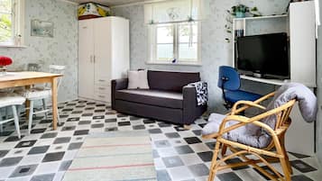 A compact living space with a sofa, a dining table, a television, and a window with a view.
