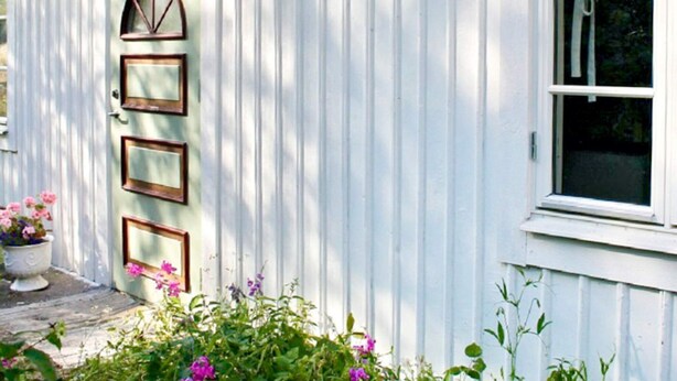 A white building with a door featuring three rectangular windows and a curved window above it. - 4 Person Holiday Home in Kopingsvik (Kopingsvik)