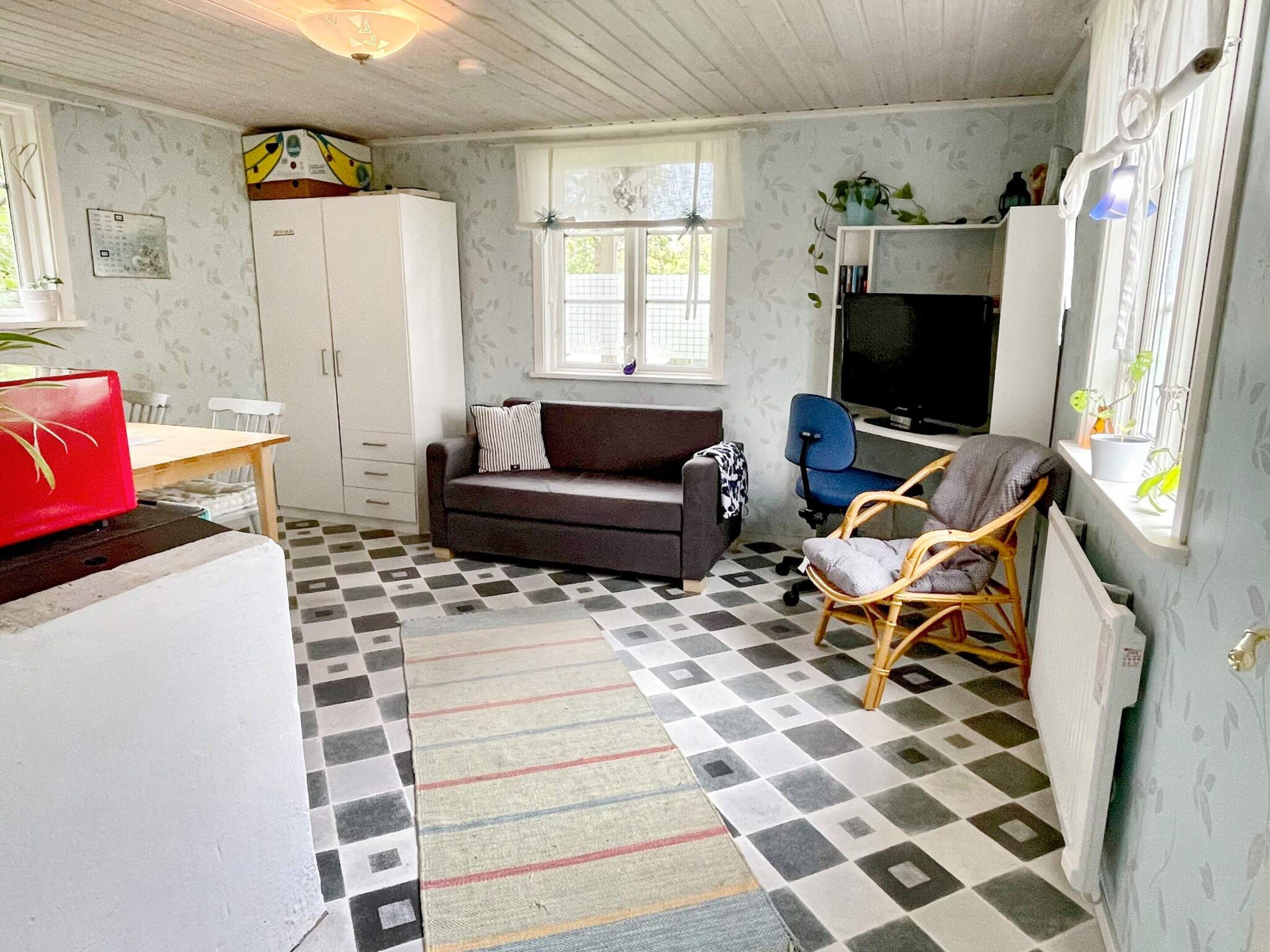 A compact living space with a sofa, a dining table, a television, and a chair.