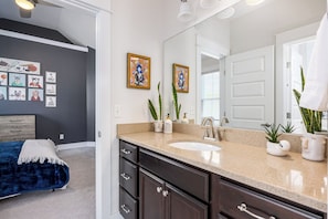 Une salle de bain moderne avec un grand miroir, des meubles sombres et un plan de toilette de couleur beige.