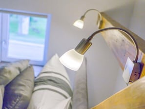 A bed with a headboard, pillows, and a bedside lamp.