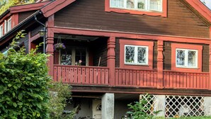 A two-story wooden house with a red facade, multiple windows, and a porch with heart-shaped railings. - 4 Star Holiday Home in Djursholm (Djursholm)
