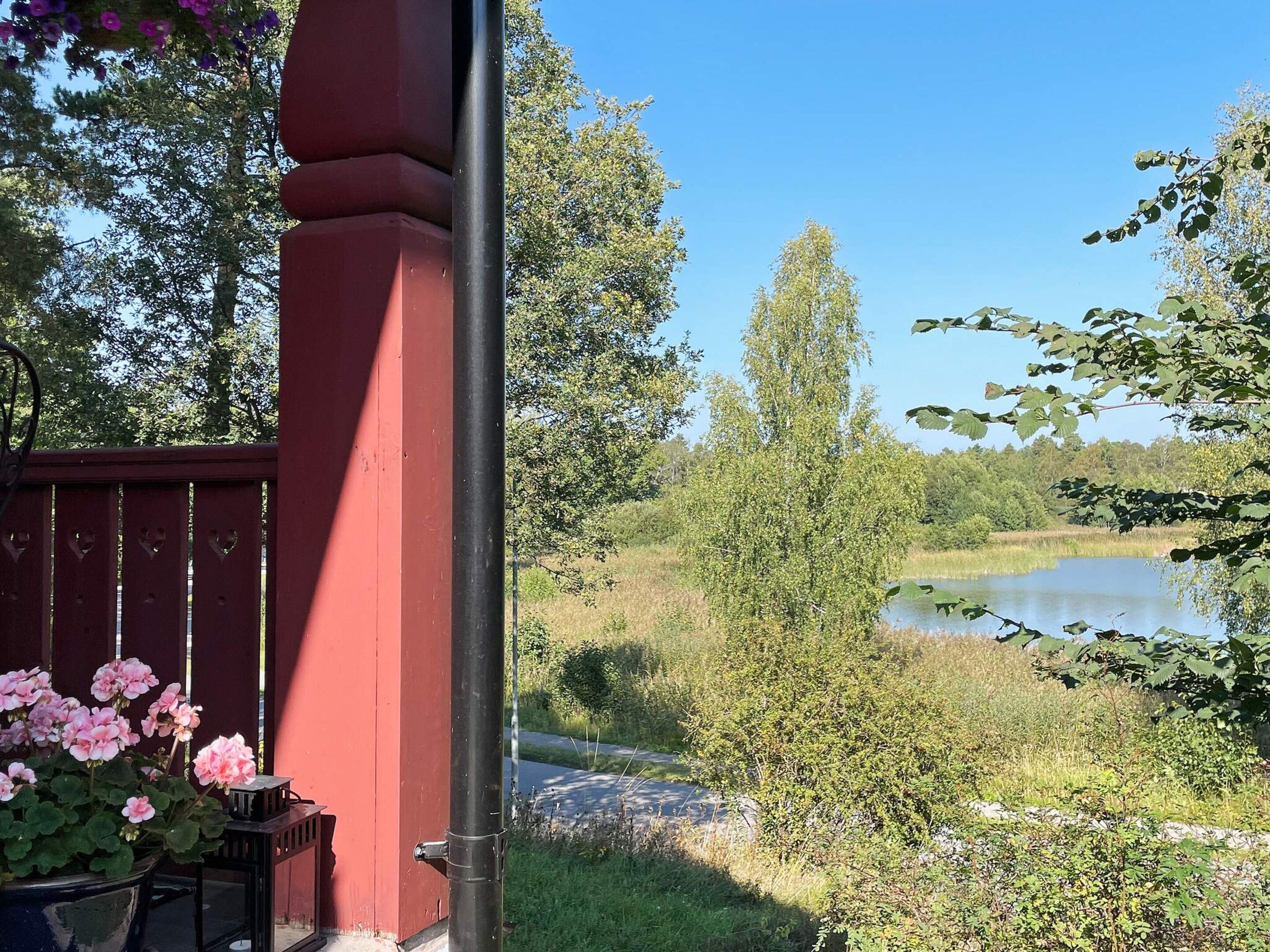 A red structure with a door, a pond, and surrounding greenery.