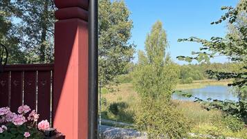A red structure with a door, a pond, and surrounding greenery.