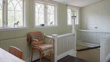 Quarto com cadeira de madeira, mesa e corrimão branco.