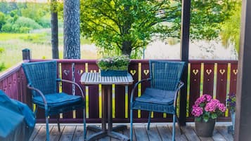 A wooden deck with two wicker chairs and a small table, surrounded by a wooden fence with heart-shaped decorations.
