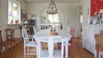 A dining area with a round table, white chairs, and a chandelier.
