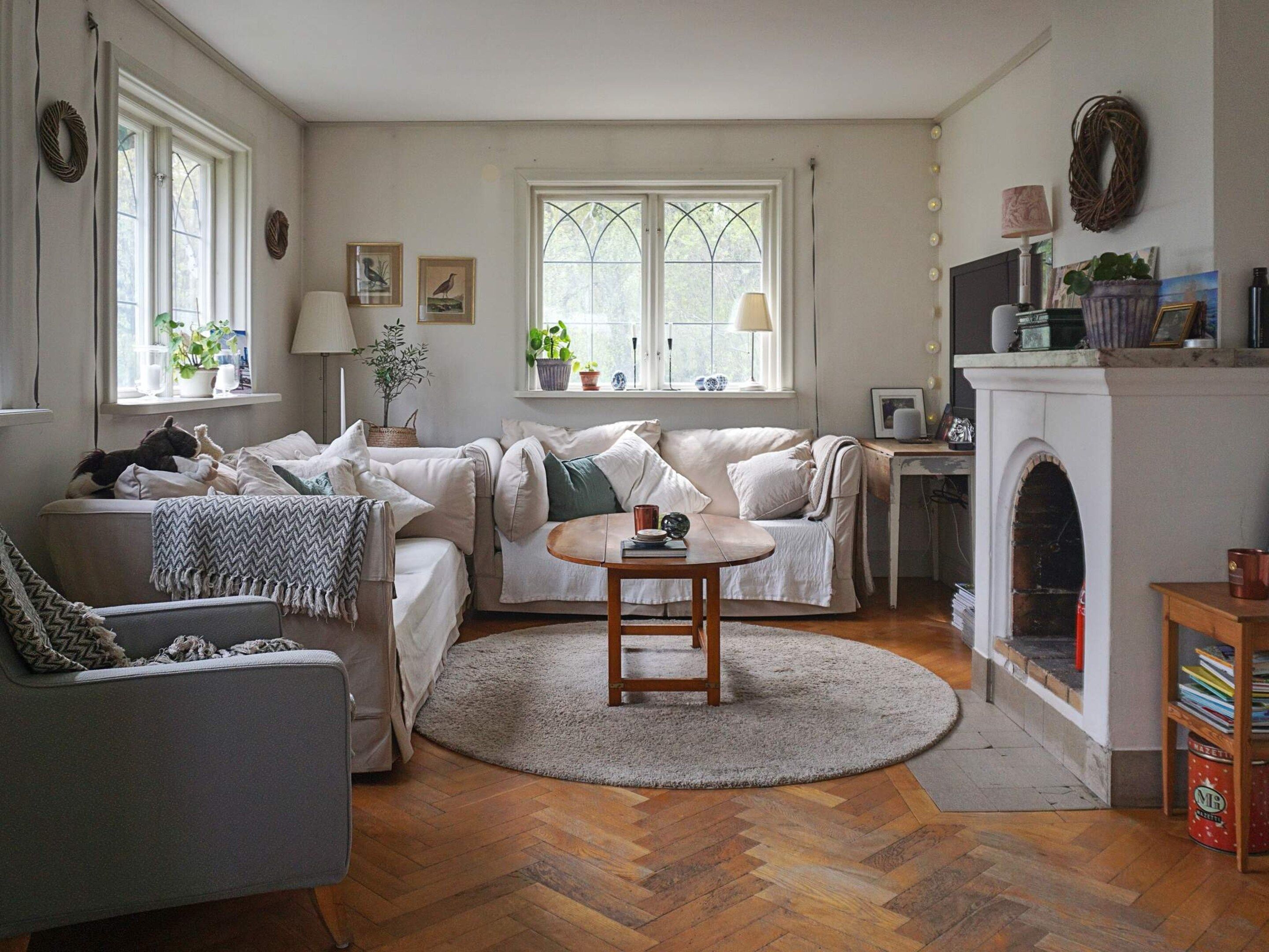 A cozy living room with a fireplace, a sofa, a table, and a bookshelf.