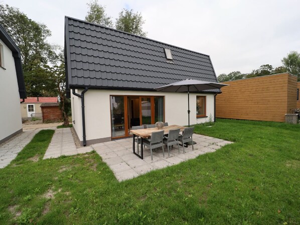 A modern house with a patio, a dining table, and chairs.