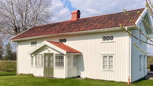 Ein weißes Gebäude mit rotem Ziegeldach, einer kleinen Veranda und einem Schornstein.