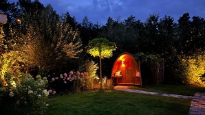 Un jardín acogedor e iluminado con un arco de madera que da a un espacio pequeño y resguardado con asientos.