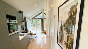 Una cocina moderna con electrodomésticos integrados, una zona de comedor con una silla y un cuadro grande en la pared.