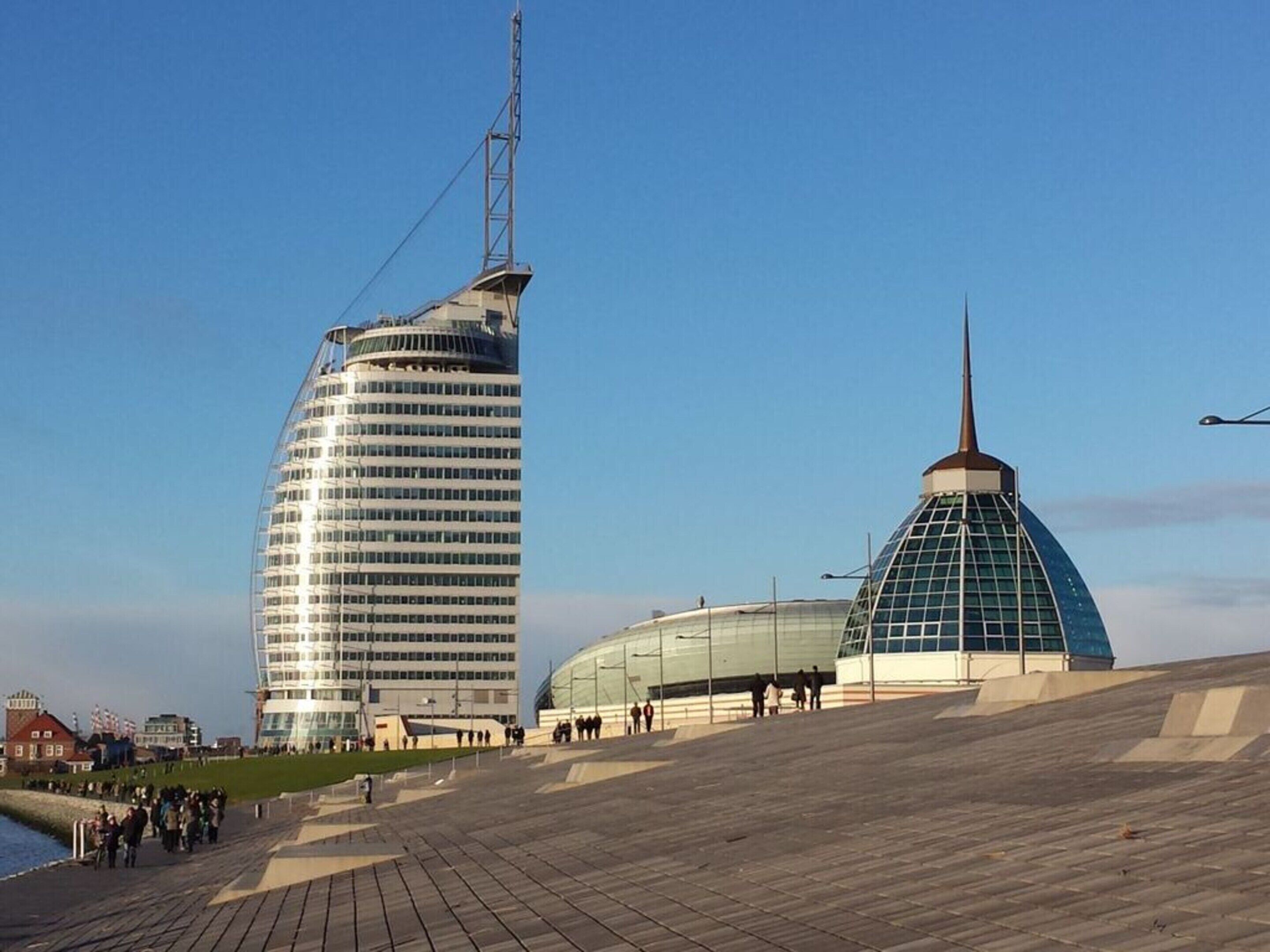 A modern building with a curved facade and a tall tower.