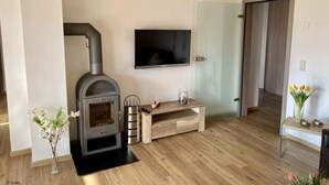 Un salon doté d’un poêle à bois, d’un téléviseur à écran plat et d’une table basse en bois.