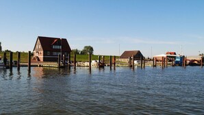 Une propriété située au bord de l’eau, comprenant une grande maison, un bâtiment plus petit et une jetée qui s’avance dans l’eau.